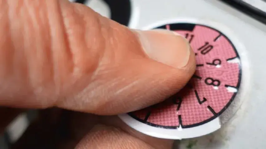 Finger entfernt TÜV-Plakette vom Nummernschild