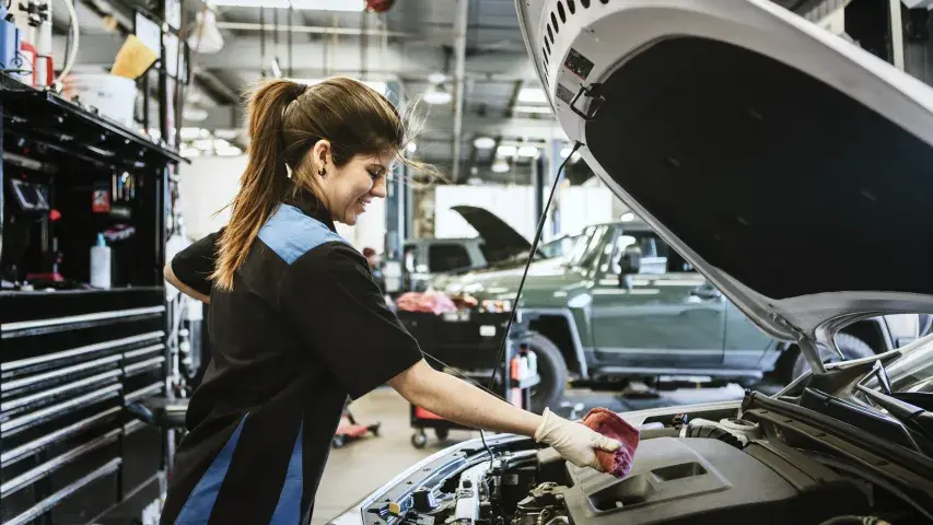women mechanic checks for oil in car